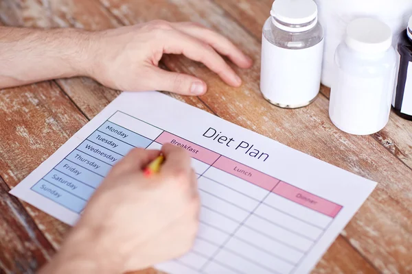 Close up of man with protein jars and diet plan — Stock Photo, Image