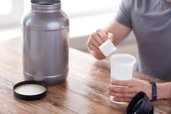 Närbild på mannen med protein shake flaska och burk — Stockfoto