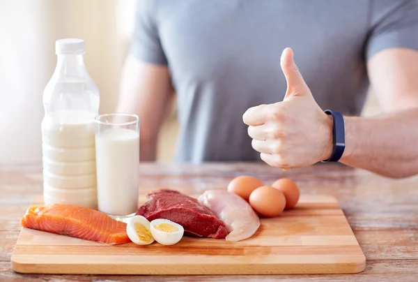 Homem com alimentos ricos em proteínas mostrando polegares para cima — Fotografia de Stock