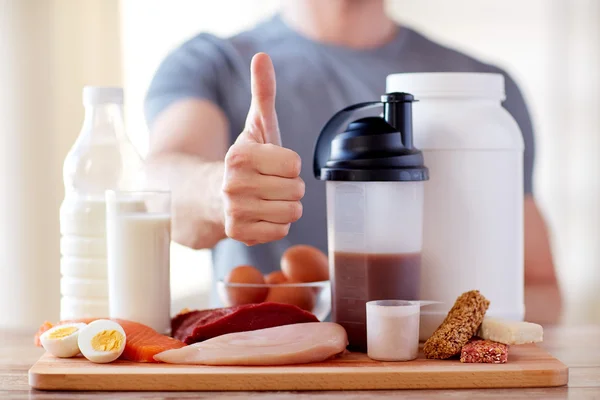 Uomo con cibo proteico mostrando pollici in su — Foto Stock