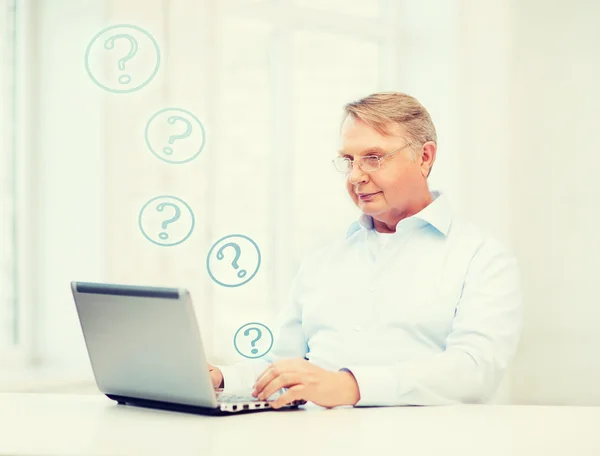 Oude man in brillen werken met laptop thuis — Stockfoto