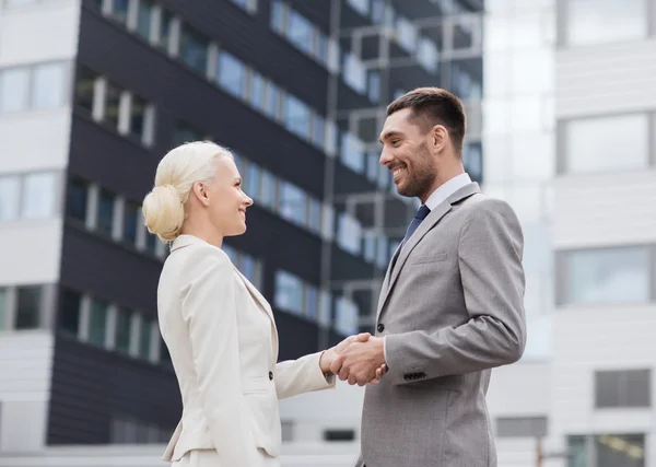 Hombres de negocios sonrientes de pie sobre el edificio de oficinas — Foto de Stock