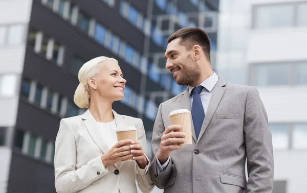 Homens de negócios sorridentes com copos de papel ao ar livre — Fotografia de Stock
