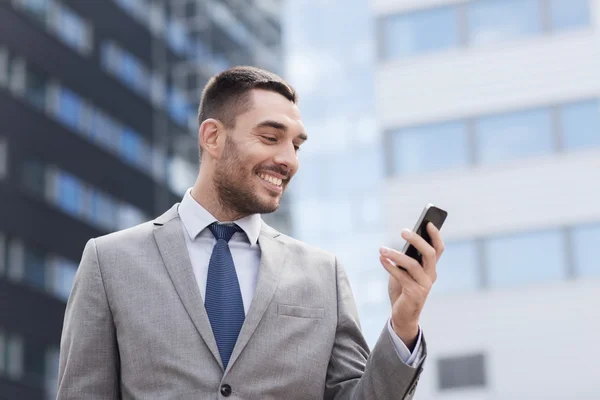 Uomo d'affari sorridente con smartphone all'aperto — Foto Stock