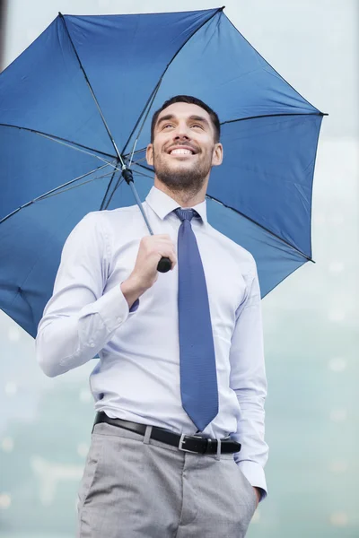 Giovane uomo d'affari sorridente con ombrello all'aperto — Foto Stock