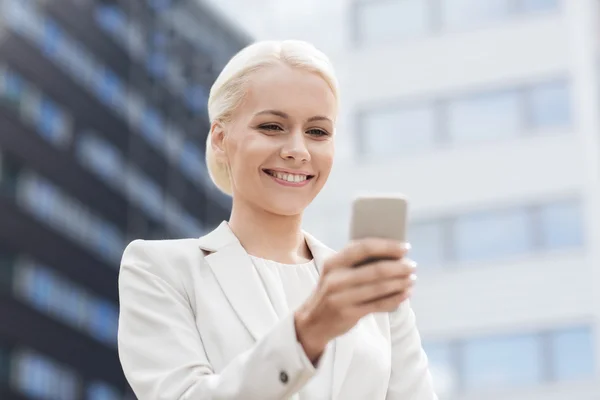 Mujer de negocios sonriente con teléfono inteligente al aire libre —  Fotos de Stock