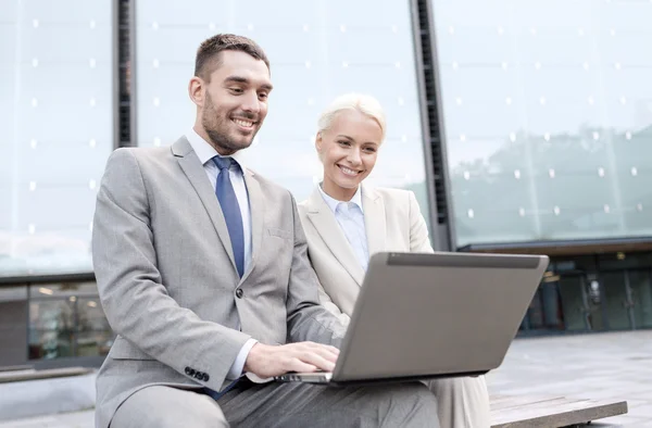 Glimlachende zakenmensen met laptop outdoors — Stockfoto