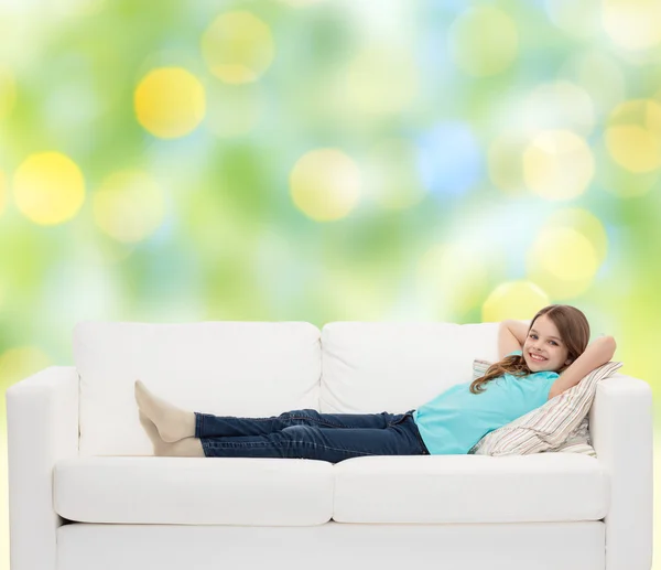 Lächelndes kleines Mädchen auf Sofa liegend — Stockfoto