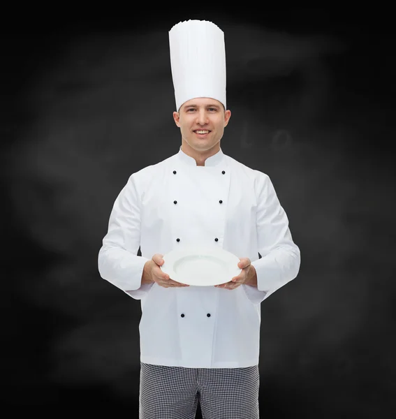 Cocinero macho feliz mostrando plato vacío —  Fotos de Stock