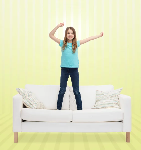 Smiling little girl jumping on sofa — Stock Photo, Image