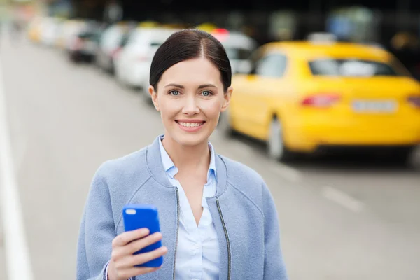 Lachende vrouw met smartphone over taxi in stad — Stockfoto