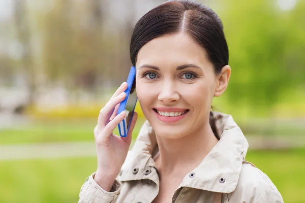 Усміхнена жінка телефонує на смартфон у парку — стокове фото