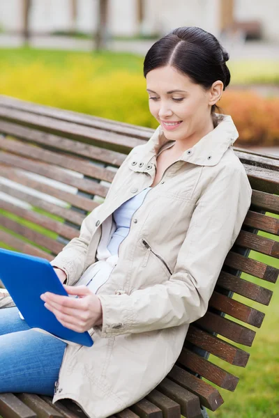 Frau mit Tablet-PC sitzt auf Bank im Park — Stockfoto