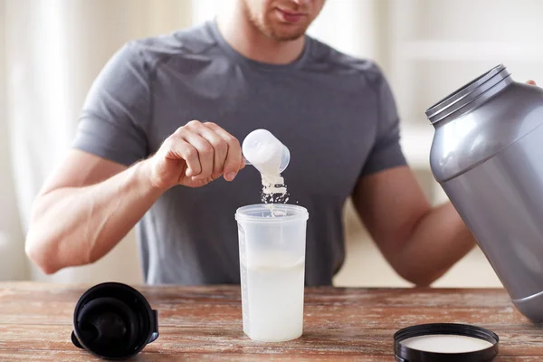 Närbild på mannen med protein shake flaska och burk — Stockfoto