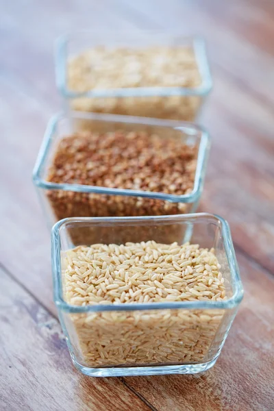 Крупним планом зерно в скляних мисках на дерев'яному столі — стокове фото