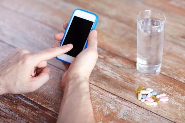 Κοντινό πλάνο χέρια με smartphone, χάπια και νερό — Φωτογραφία Αρχείου