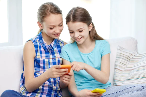 happy girls with smartphones sitting on sofa