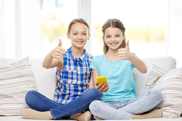 Happy girls with smartphone sitting on sofa Stock Picture