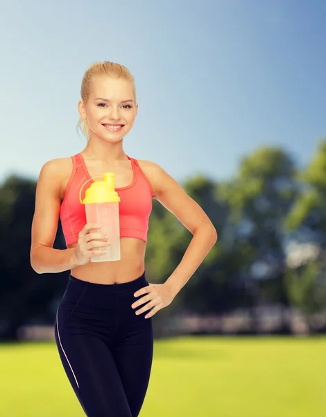 Lächelnde sportliche Frau mit Protein-Shake-Flasche — Stockfoto