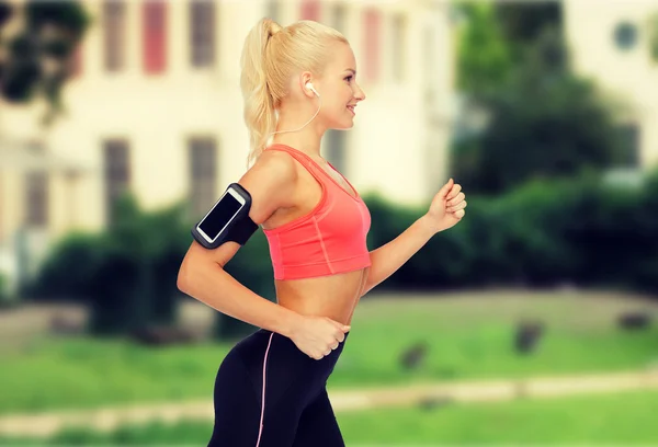 Mujer deportiva corriendo con smartphone y auriculares —  Fotos de Stock