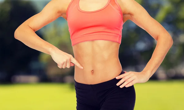 Close up of woman pointing finger at her six pack — Stock Photo, Image