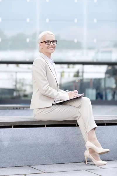 Jeune femme d'affaires souriante avec bloc-notes à l'extérieur — Photo