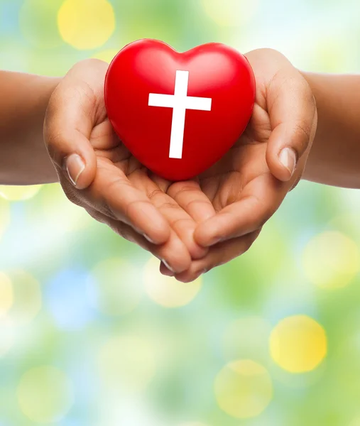 Close up of hands holding heart with cross symbol — Stock Photo, Image