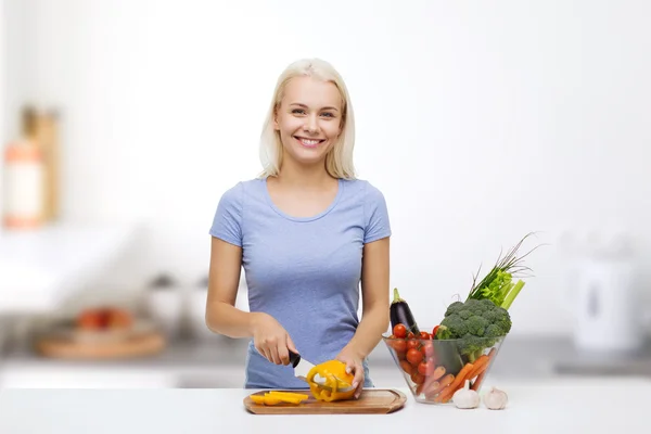 Leende ung kvinna hugga grönsaker på kök — Stockfoto