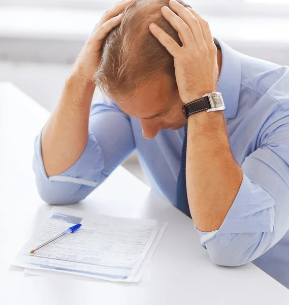 Stressed businessman with papers at work Stock Picture