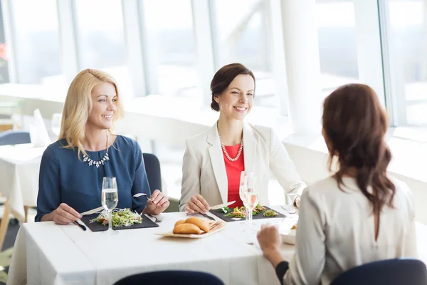 Happy women eating and talking at restaurant — Stock Photo, Image