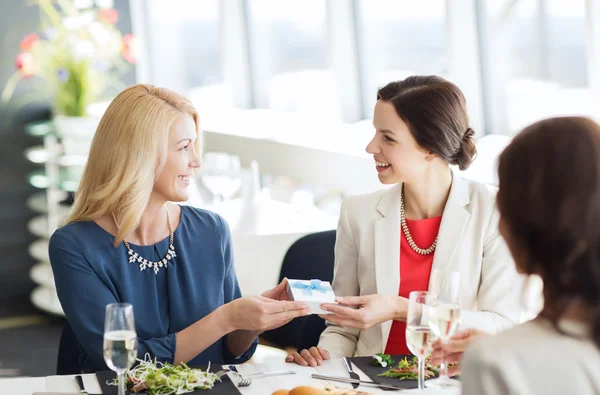 Glada kvinnor ger födelsedagspresent på restaurang — Stockfoto