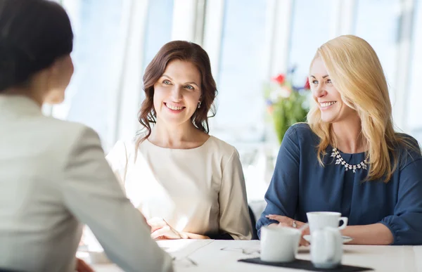 women drinking coffee and talking at restaurant