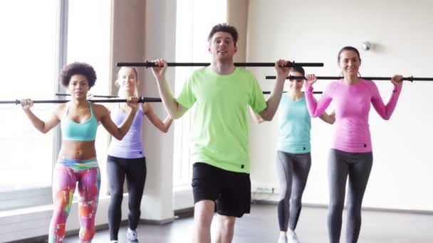 Gruppe von Menschen, die mit Bars im Fitnessstudio trainieren — Stockvideo