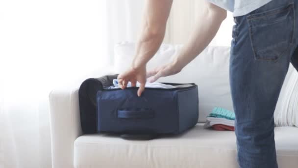 Close up of man packing clothes into travel bag — Stock Video