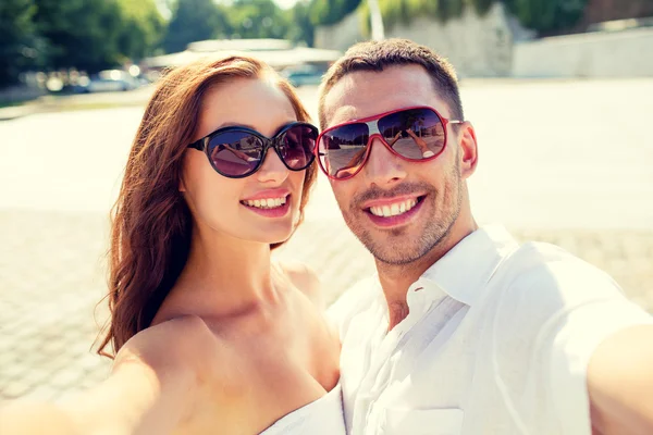 Sonriente pareja usando gafas de sol haciendo selfie — Foto de Stock