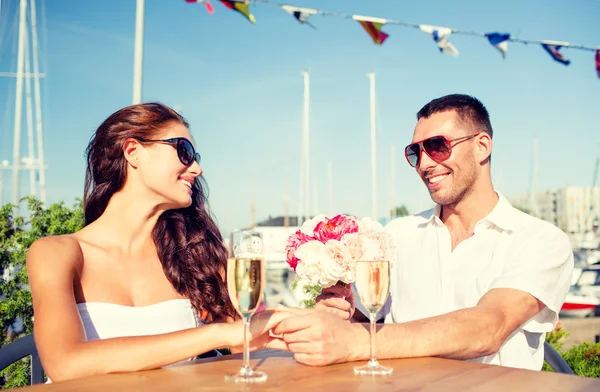 Lächelndes Paar mit Strauß und Champagner im Café — Stockfoto