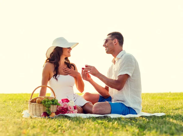 Couple souriant avec petit coffret cadeau rouge sur pique-nique — Photo