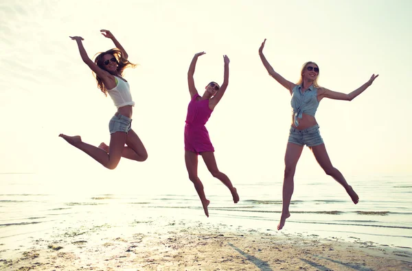 Happy female friends dancing and jumping on beach — Stock Photo, Image