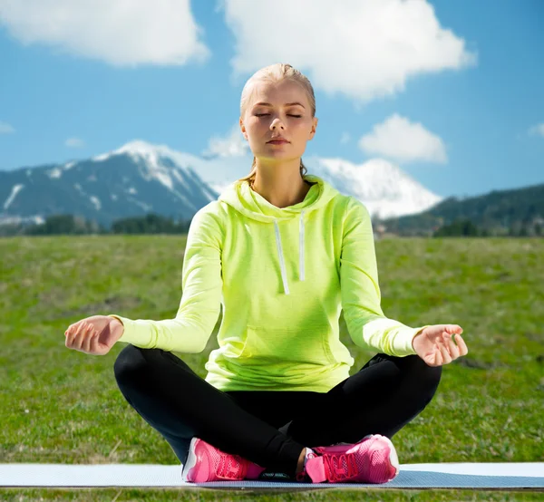 Mujer sentada en pose de loto haciendo yoga al aire libre — Foto de Stock