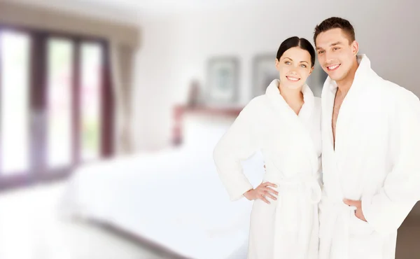 Feliz pareja en albornoces sobre la habitación de hotel spa —  Fotos de Stock