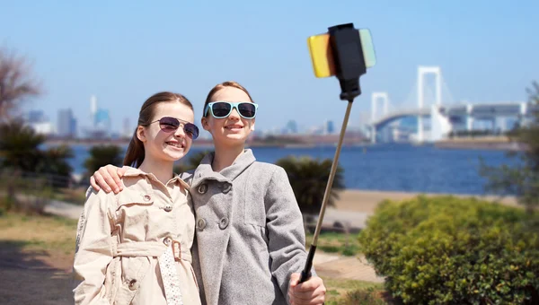 Happy girls with smartphone selfie stick in tokyo — Stock Photo, Image