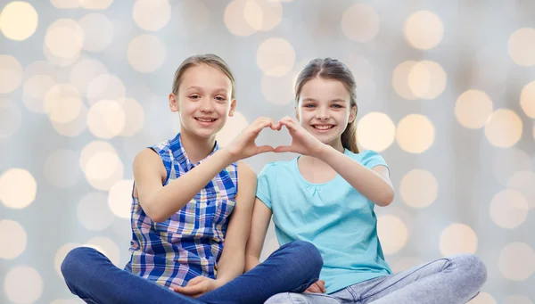 Happy little girls showing heart shape hand sign — Stock Photo, Image