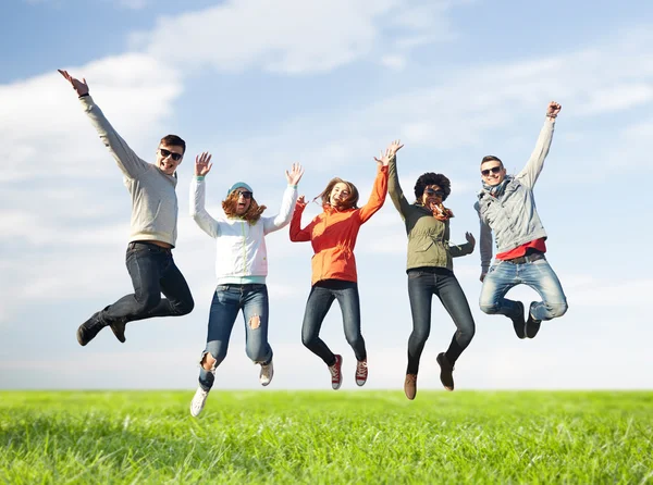 Ler vänner i solglasögon hoppar högt — Stockfoto