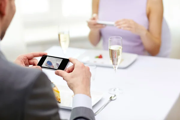 Närbild på par med smartphones på restaurang — Stockfoto