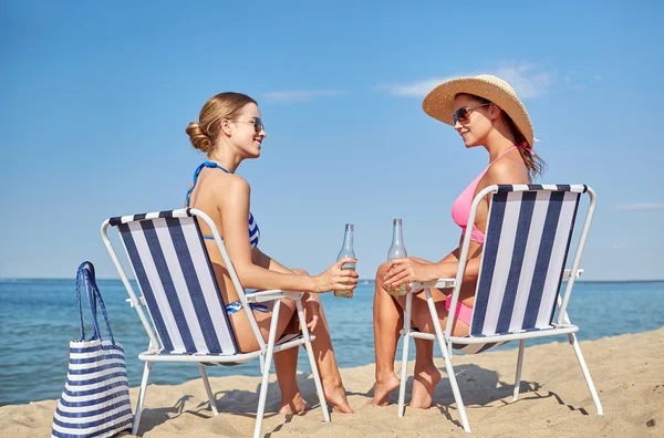 Mujeres felices tomando el sol en salones en la playa — Foto de Stock