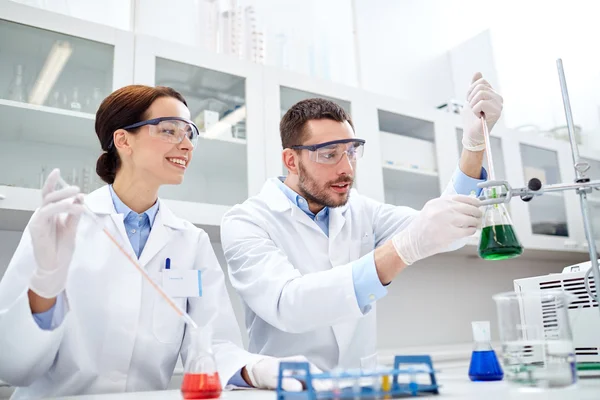 Jóvenes científicos haciendo pruebas o investigaciones en laboratorio — Foto de Stock