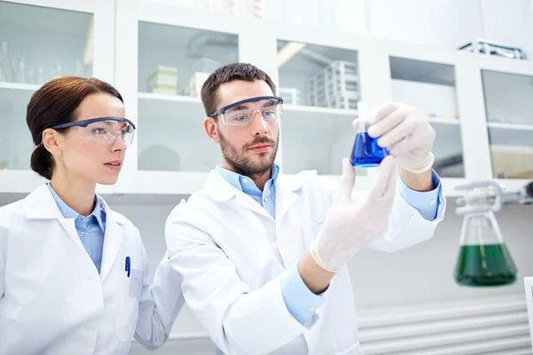 Jóvenes científicos haciendo pruebas o investigaciones en laboratorio — Foto de Stock