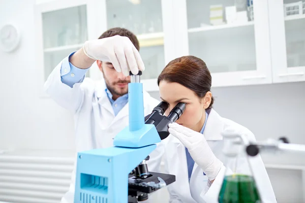 Jóvenes científicos haciendo pruebas o investigaciones en laboratorio — Foto de Stock