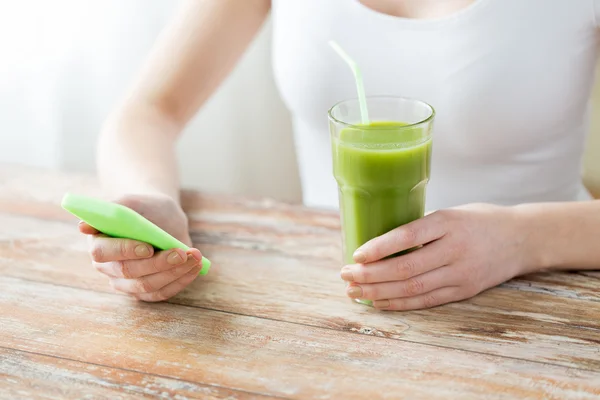 Close up of woman with smartphone and green juice — Stock Photo, Image