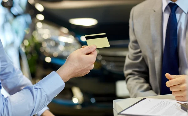 Клиент дает кредитную карту автодилеру в салоне — стоковое фото